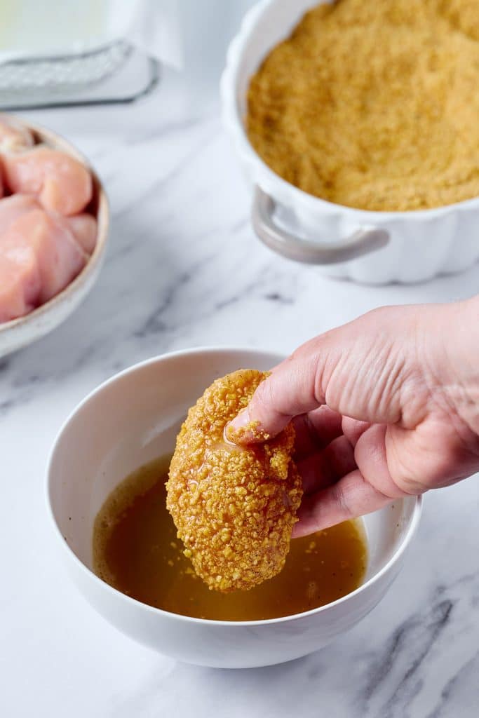 dipping crumb coated chicken into egg wash 