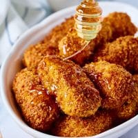 drizzling hot honey over pieces of crispy chicken