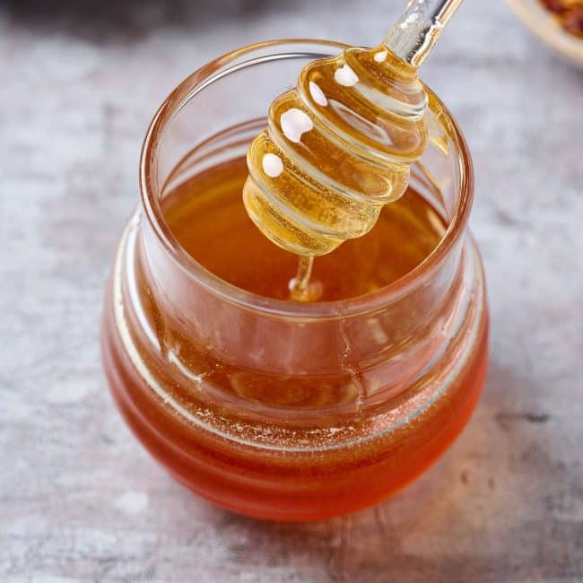 hot honey in a small jar with a dipper
