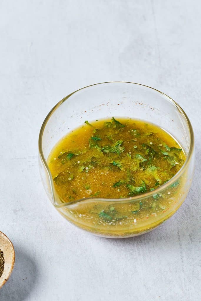 lime dressing with cilantro in a small clear bowl