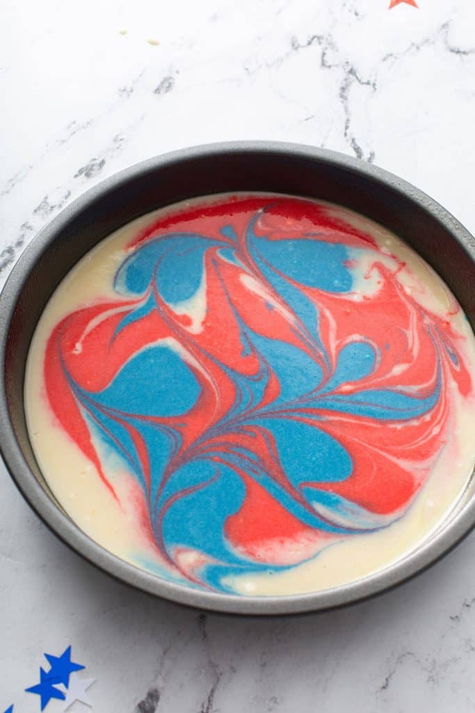 Red, white and blue marbled cake batter in a baking pan.