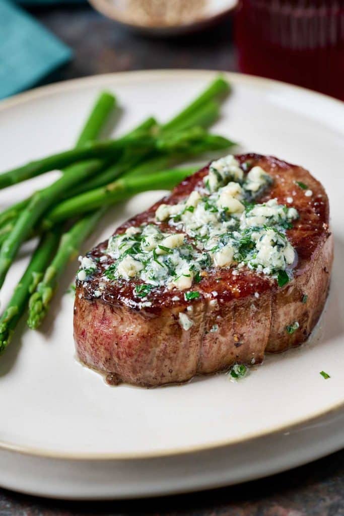 Perfectly cooked steak topped with blue cheese butter served with asparagus.