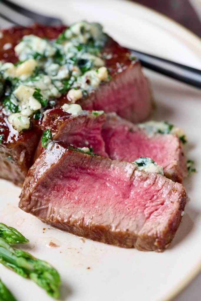 Sliced steak topped with herb blue cheese butter.