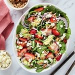 strawberries, red onions and spinach salad in a bowl