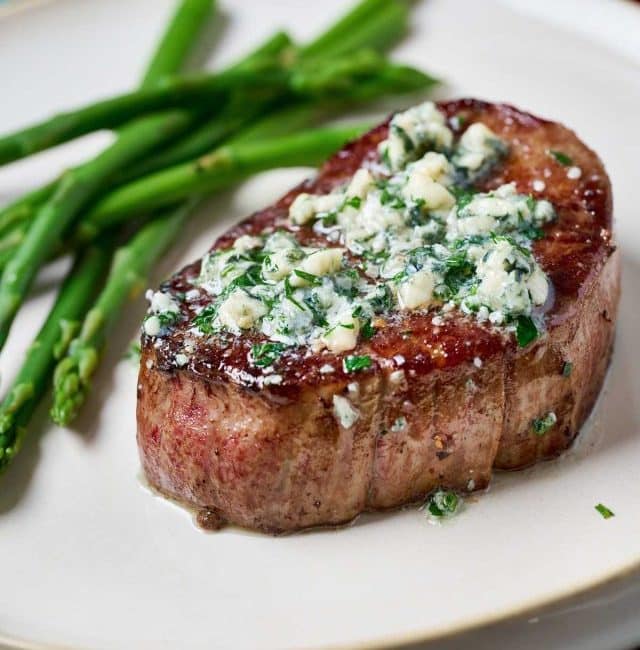 Perfectly cooked steak topped with blue cheese butter served with asparagus.
