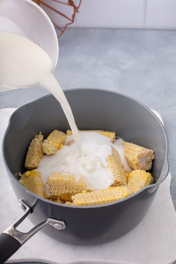 pouring a milk mixture over corn cobs