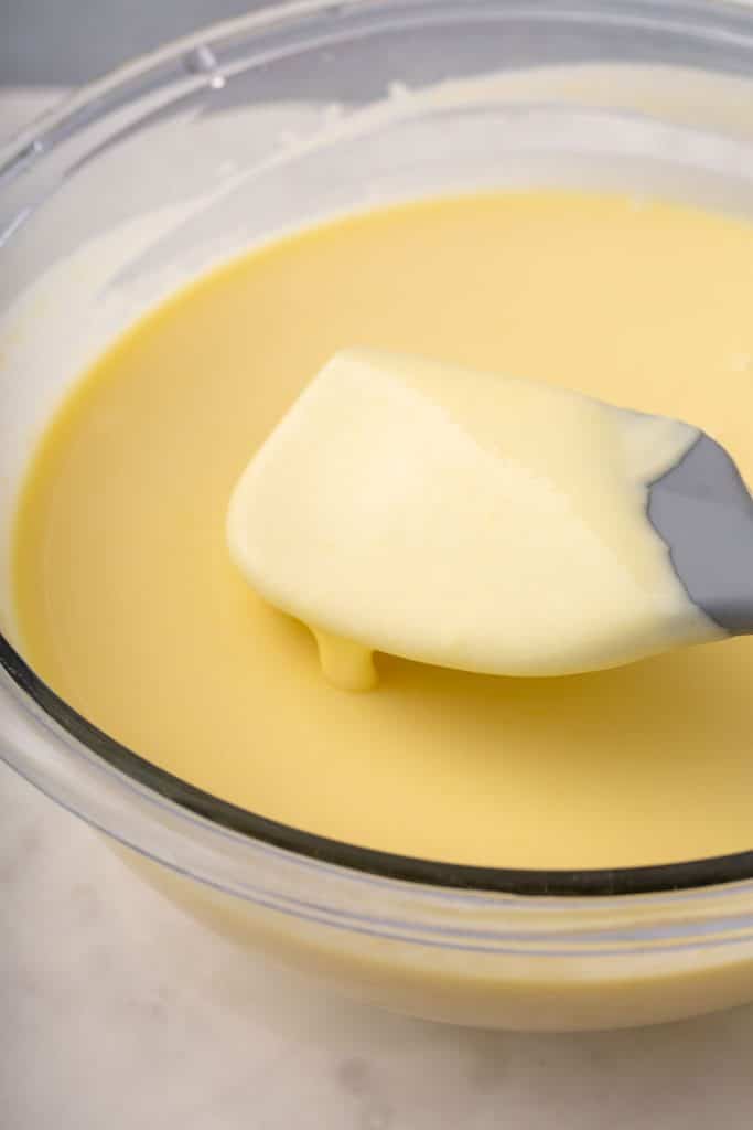 creamy egg yolk-corn mixture in a mixing bowl with a gray spatula