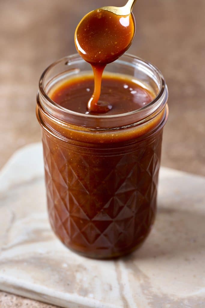 drizzling caramel sauce with a spoon on a jar