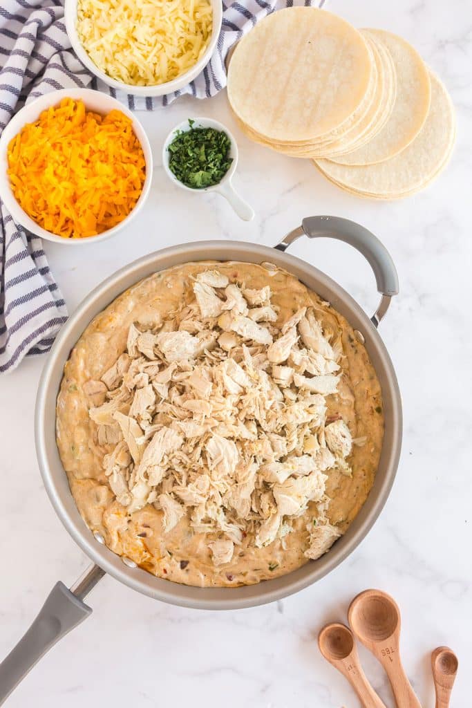 Cheesy sauce topped with shredded chicken in a skillet