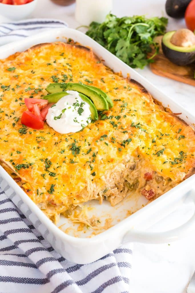 A chicken and cheese casserole topped with sour cream, chopped tomatoes and sliced avocado.