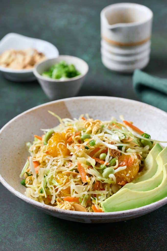 A serving of ramen salad in a bowl with sliced avocado.