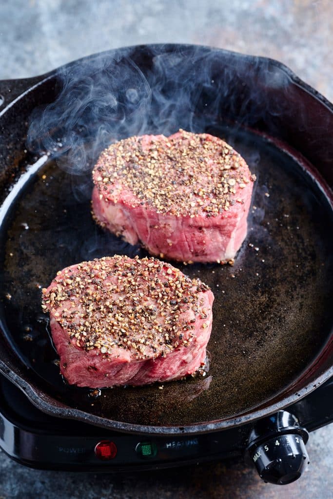 Searing peppered steaks in a cast iron skillet