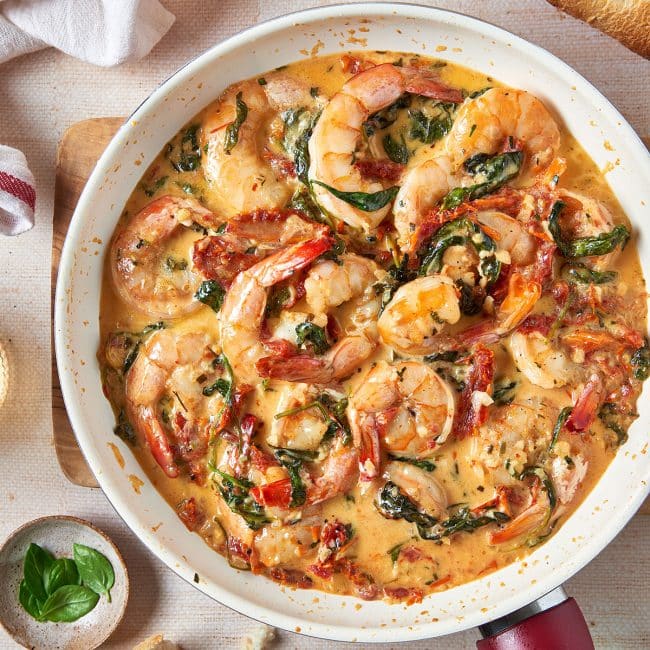ceamy shrimp with sundried tomatoes and spinach in a skillet