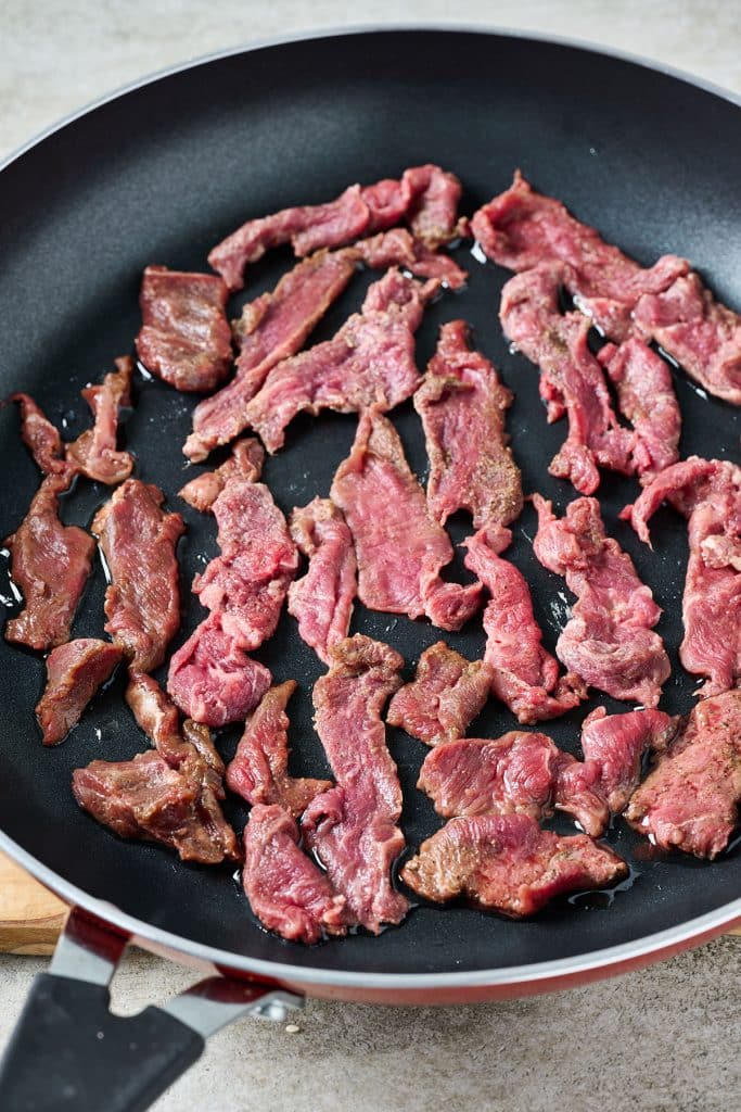 sliced flank steak cooking on a pan