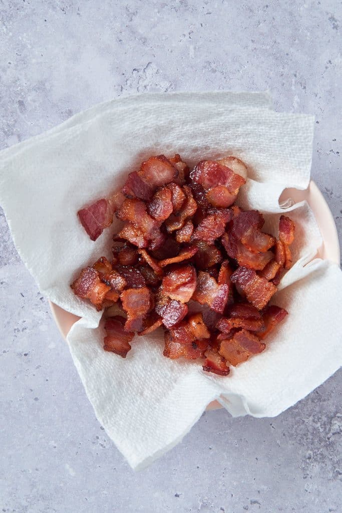 Crispy bacon draining on a plate with paper towels
