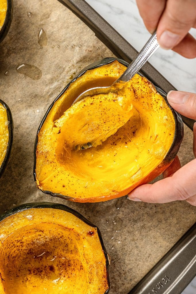 Scooping some of the flesh of a roasted acorn squash