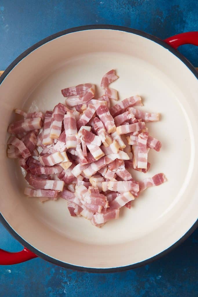 Raw bacon pieces in a soup pot.