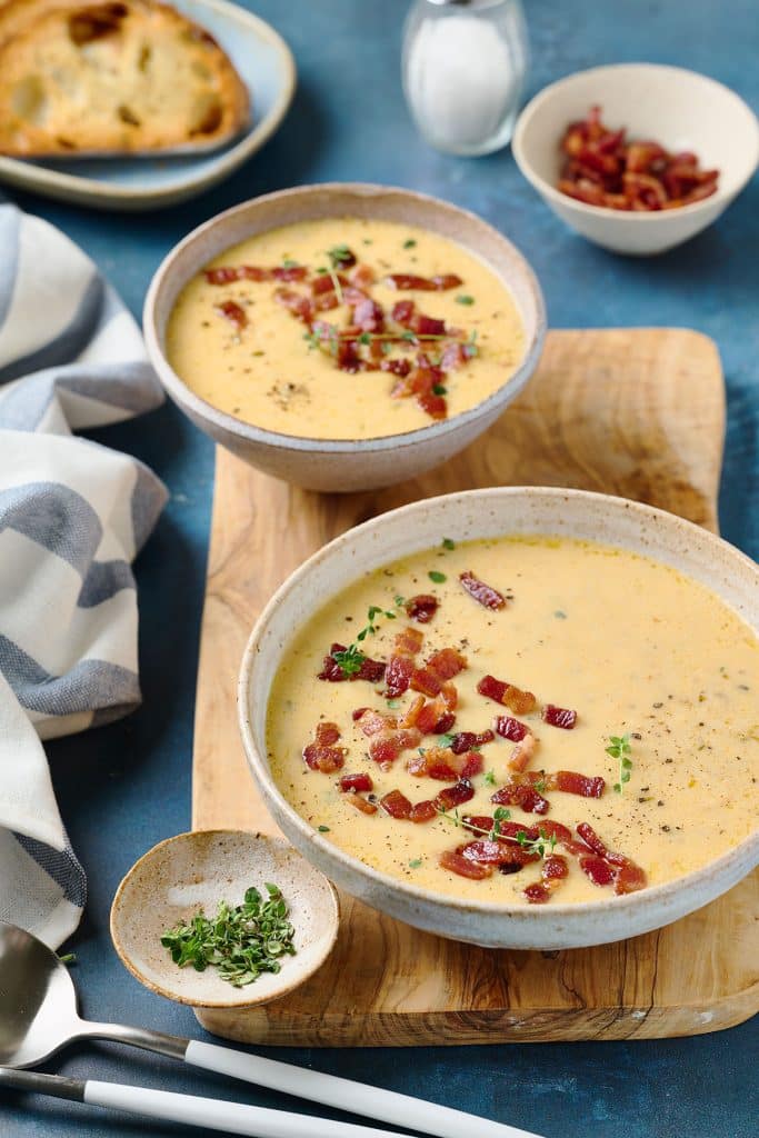 bowls filled with creamy beer and cheese soup topped with crispy bacon