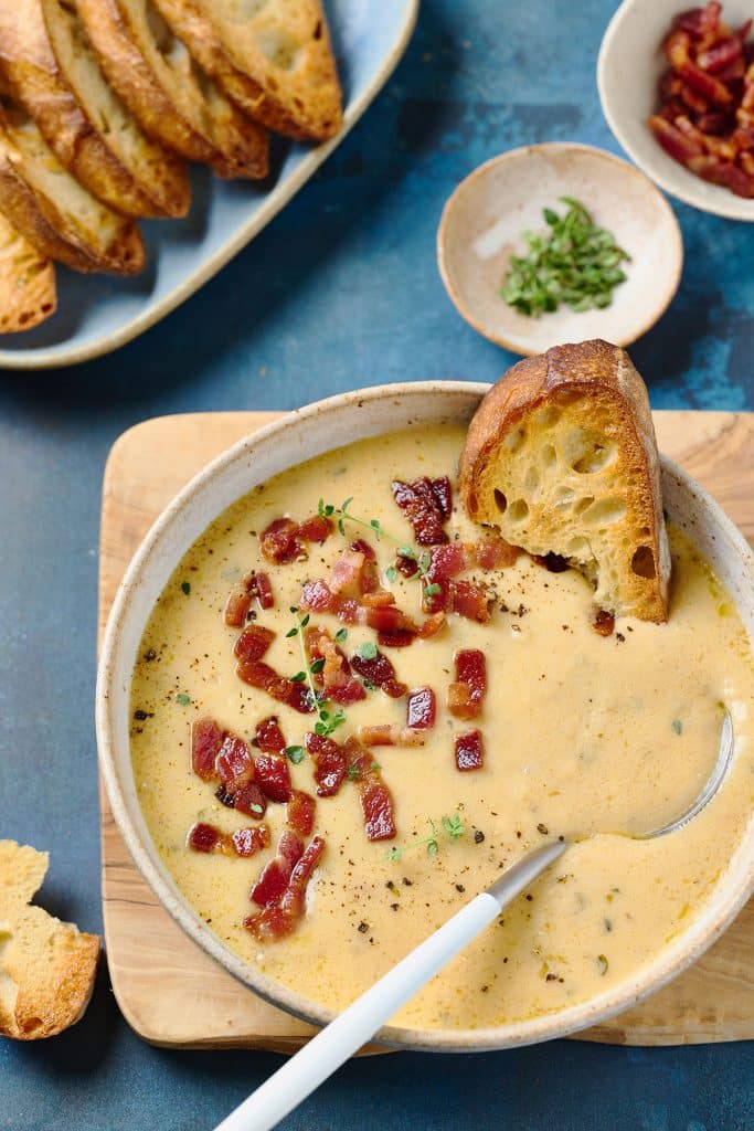 Spoon in a bowl of creamy soup served with rustic bread