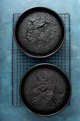two round pans with black velvet cake on a cooling rack