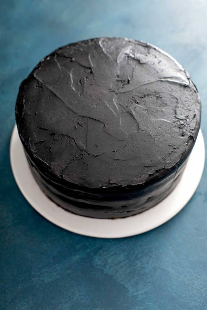 black frosting spread evenly over the black velvet cake