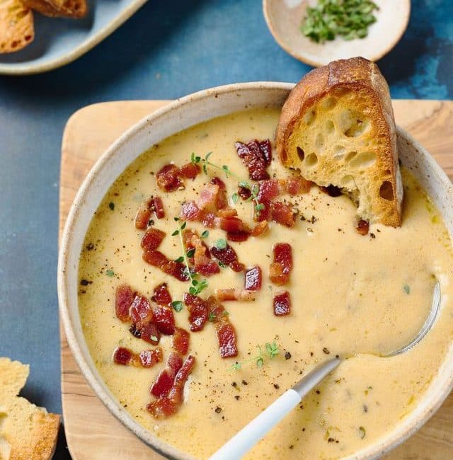 Spoon in a bowl of creamy soup served with rustic bread