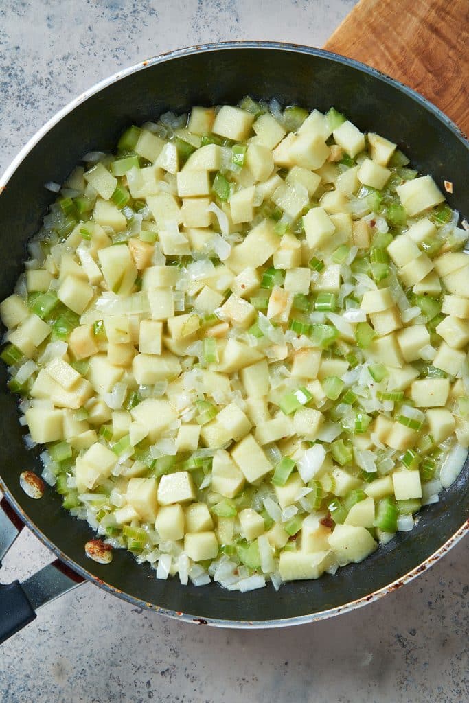 soft onions, celery and apples on a skillet