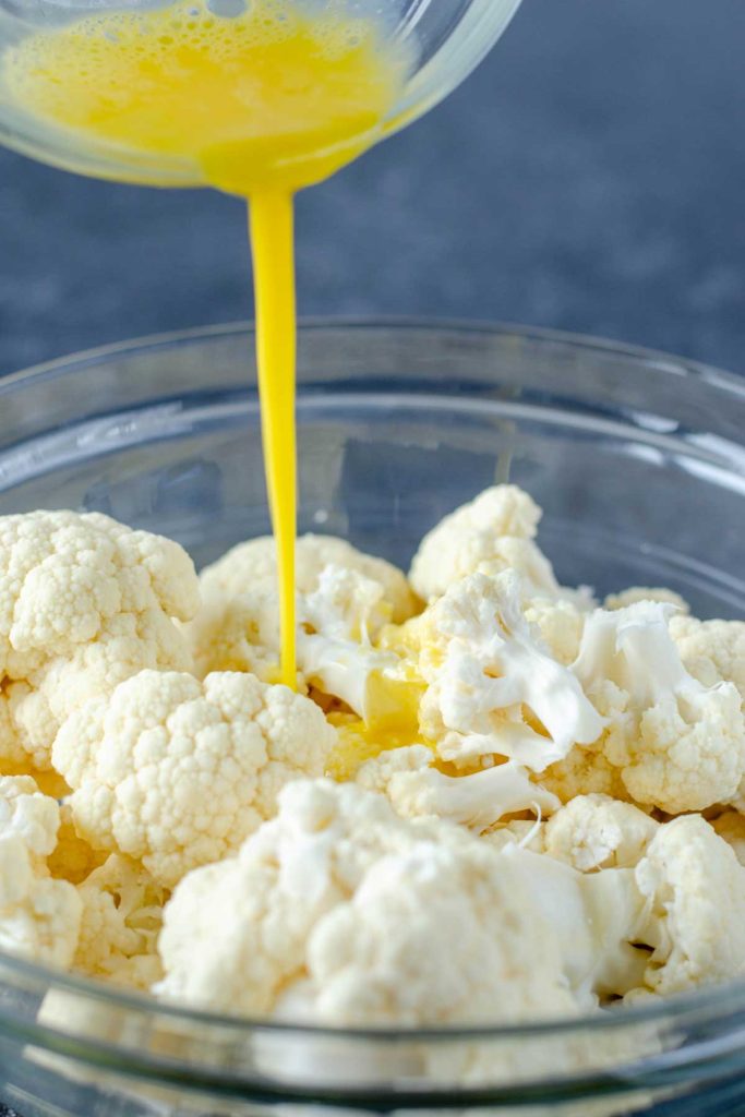 Pouring whisked egg over cauliflower florets