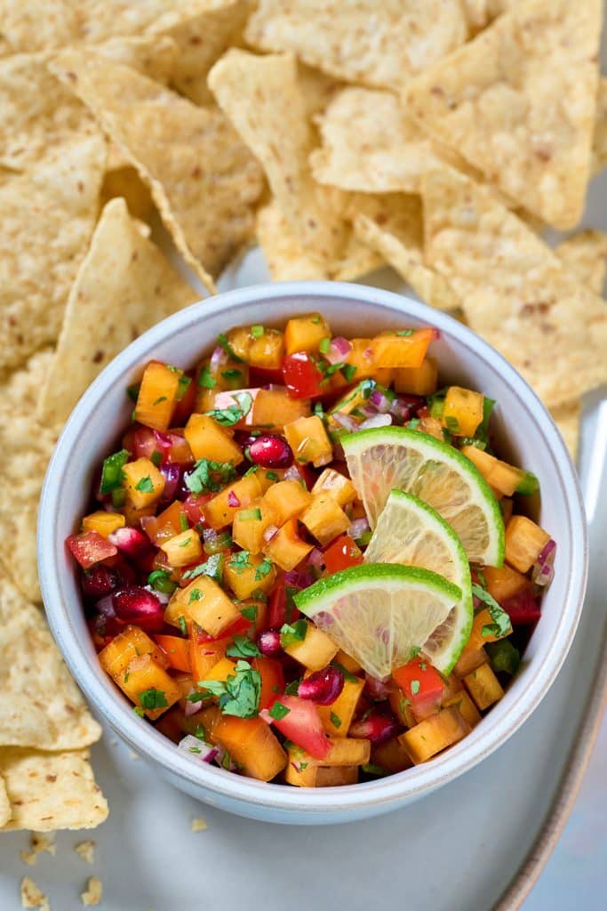 A bowl of persimmon salsa surrounded with tortilla chips