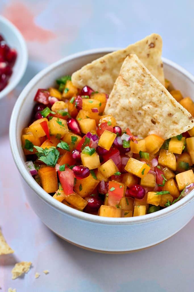 a small bowl with persimmon salsa garnished with tortilla chips.
