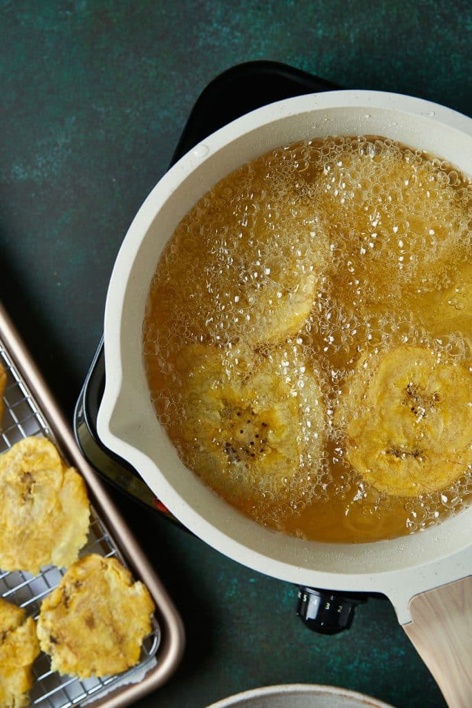 Smashed tostones frying in a pot