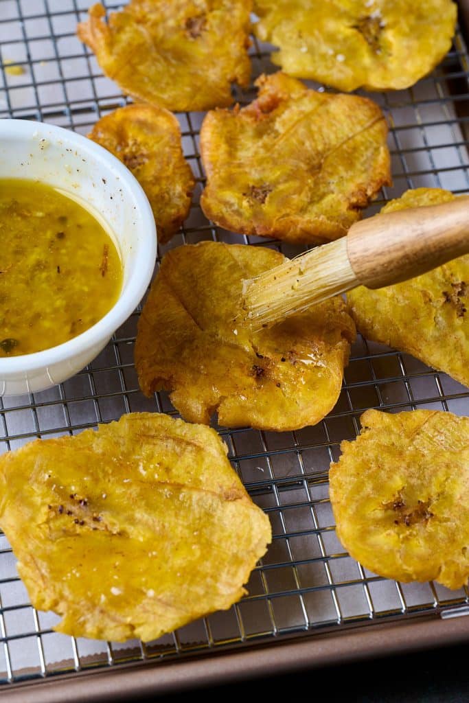 Tostones brushed with mojo sauce and topped with salt while still hot right off the skillet
