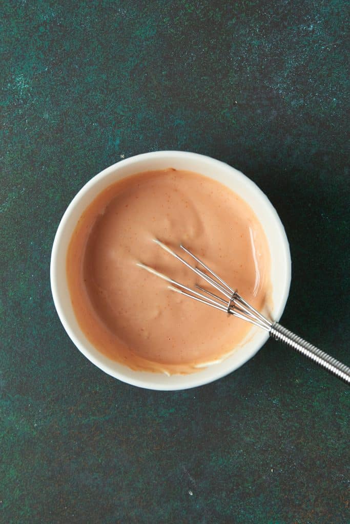 Mayonnaise, ketchup, and minced garlic whisked in a bowl to make ketchup mayo, mayo ketchup