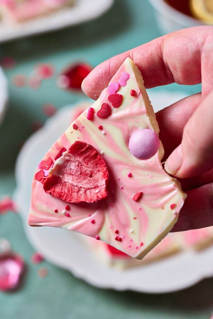 Holding a piece of white chocolate bark with valentine's day decorations.