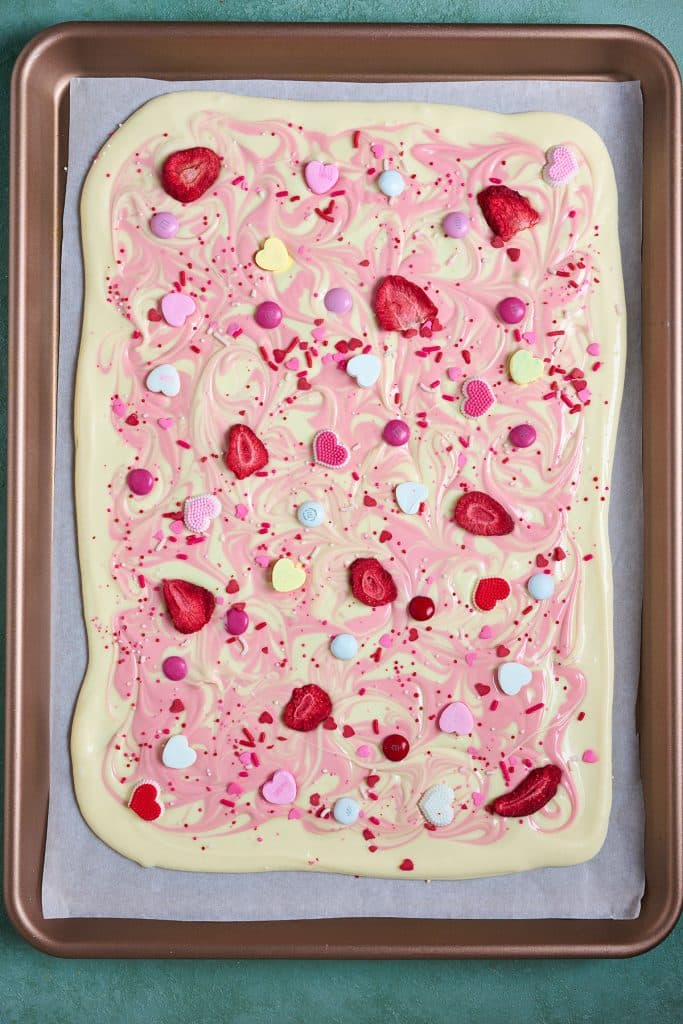 Valentine's day white chocolate bark with candies and freeze dried fruit on a sheet pan