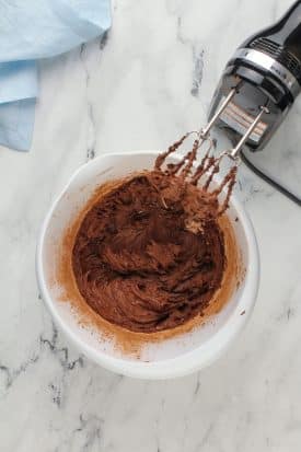 mixing vegan chocolate frosting ingredients in a bowl