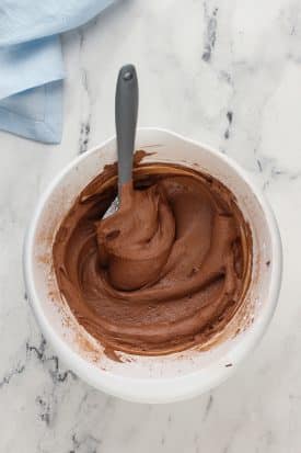 vegan chocolate buttercream in a large white bowl with a gray spatula