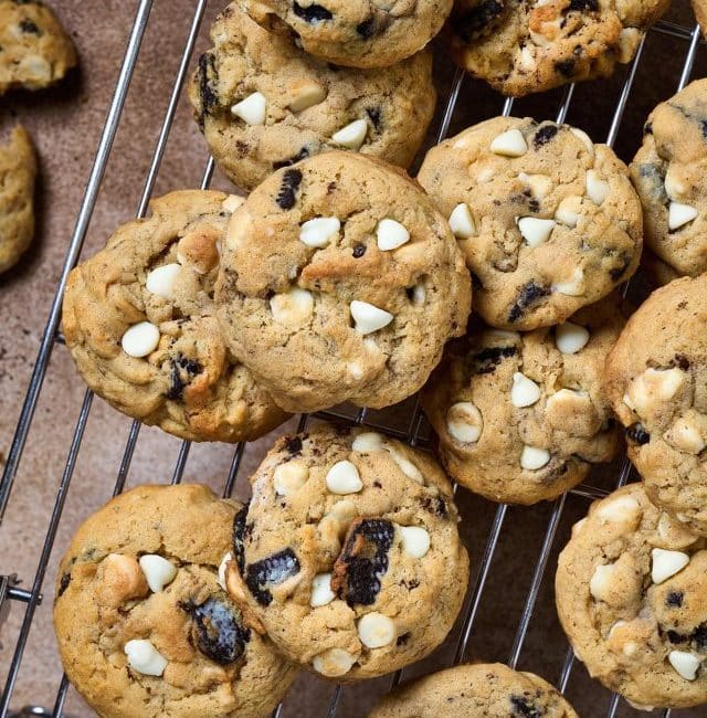 Baked cookies with white chocolate chips and oreo chunks on a cooling rack.