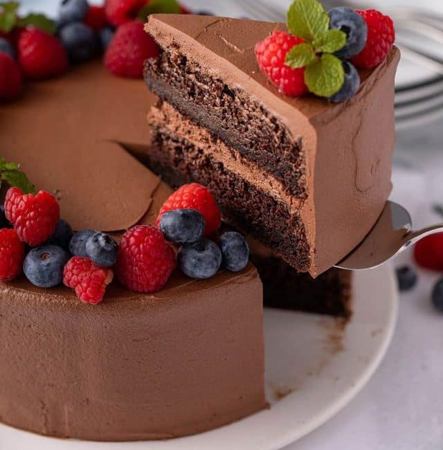 cutting a slices of vegan chocolate cake from a cake stand