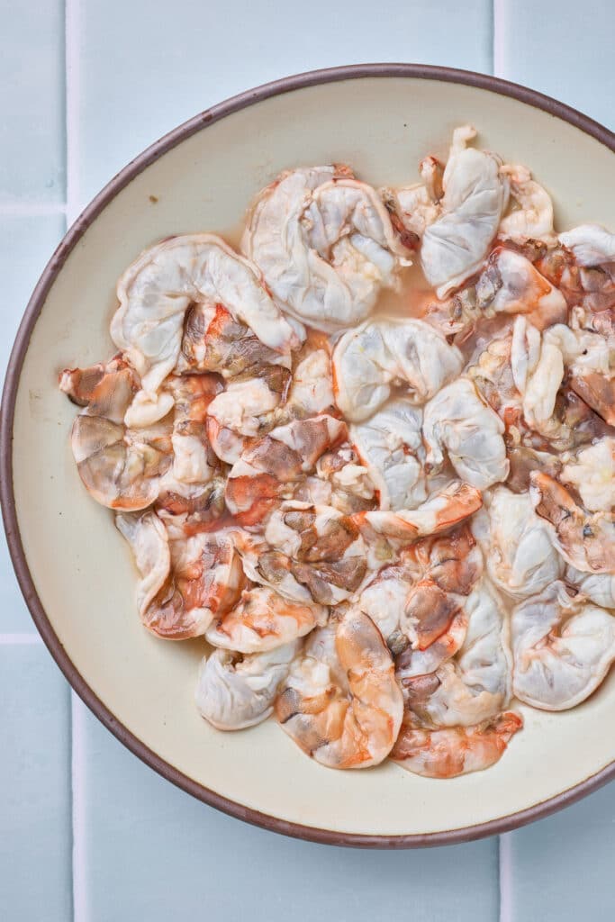 Shrimp partially cooked in lime juice on a plate.