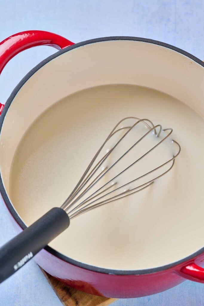 A whisk set in a Dutch oven filled with a liquid mixture