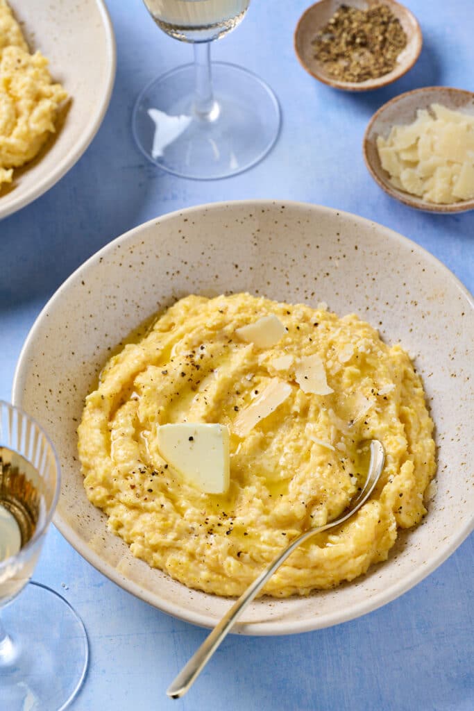 A bowl with polenta topped with melty butter, Parmesan cheese and ground black pepper