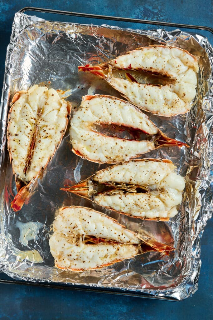Cooked lobster tails on a sheet pan covered with aluminum foil