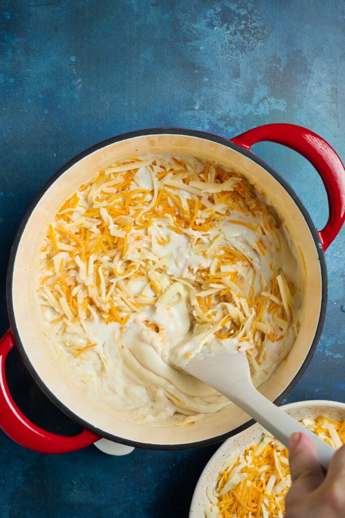 melting cheese into white sauce in a pot