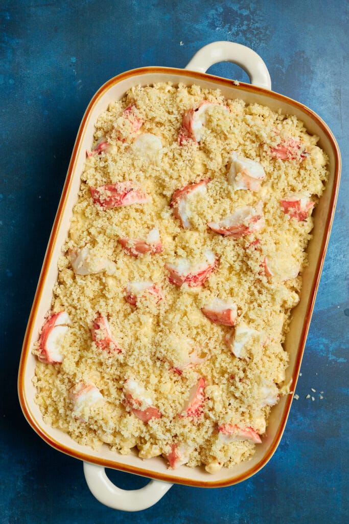 Macaroni and cheese in a baking dish topped with lobster chunks and a panko bread topping