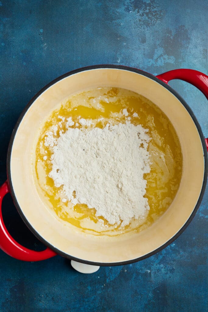 Combining melted butter and flour in a pot to make a roux.