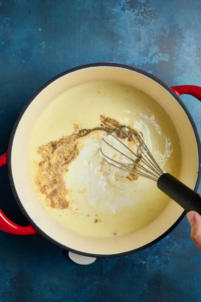 adding seasonings into creamy white sauce or béchamel sauce