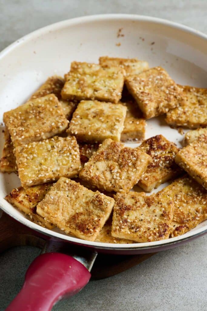 Pan frying tofu pieces on a skillet.
