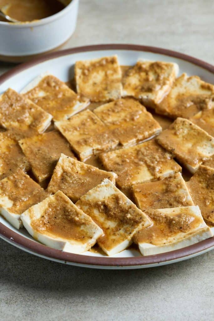 Tofu slices marinating on a plate