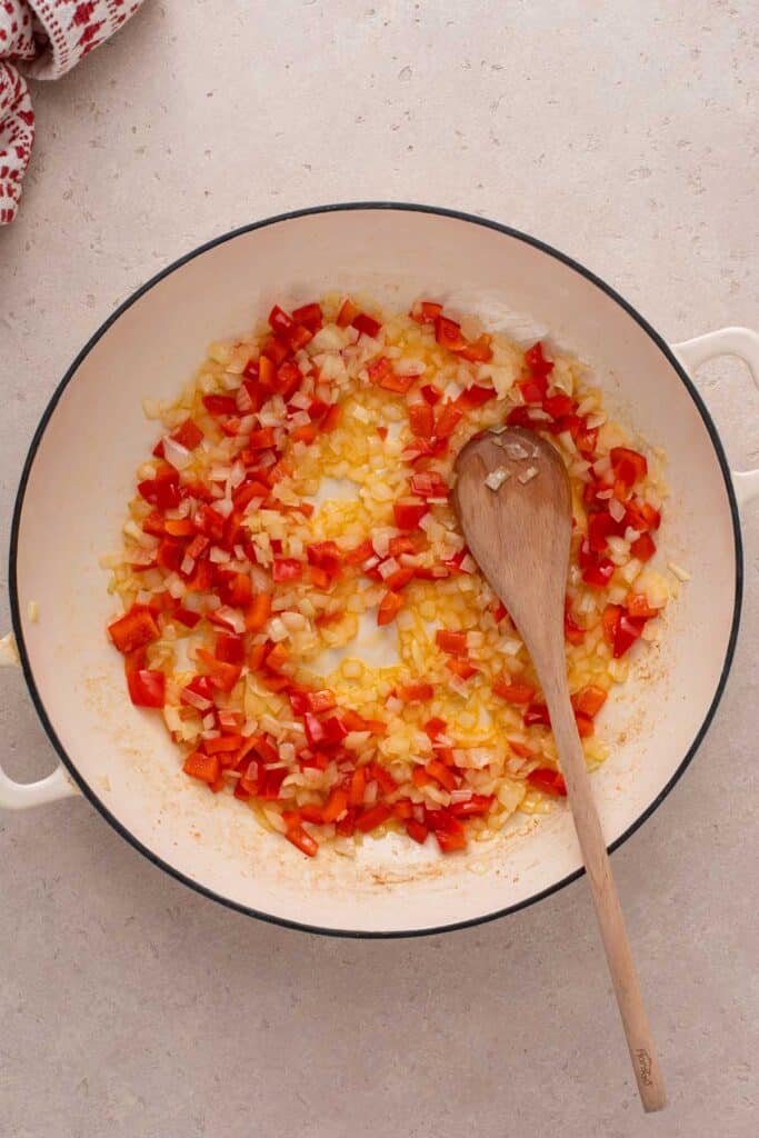 Sautéing onions and bell peppers in oil in a skillet